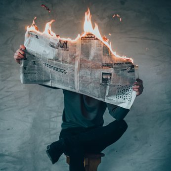 Man holding a newspaper on fire