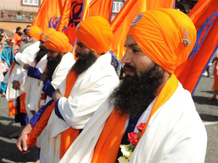 Sikhs lined up with bright orange turbans. 