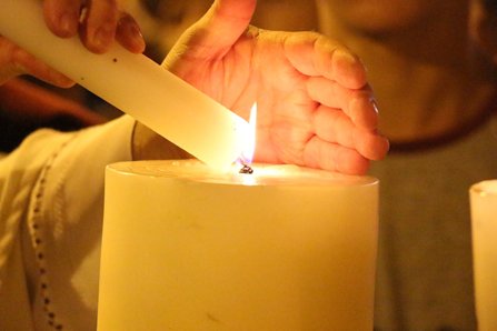 A man in a religious outfit lights a candle