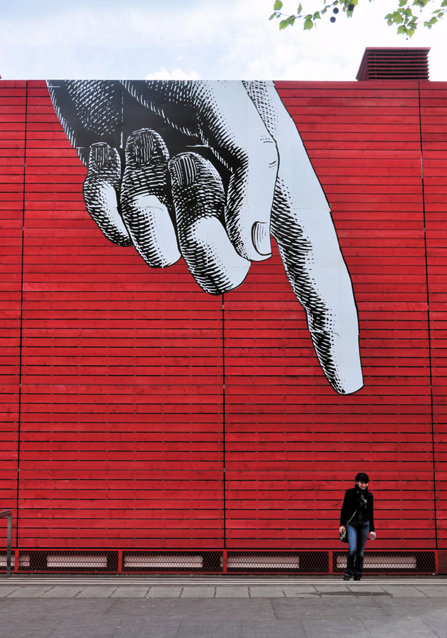 A painting on a wall with a giant hand and a finger pointing