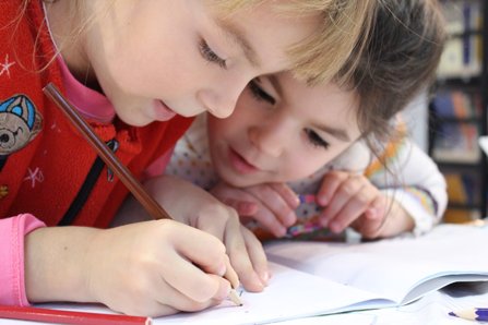 Two girls focused on drawing on a piece of paper