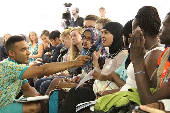 A woman in a hijab in an audience is given the microphone to speak