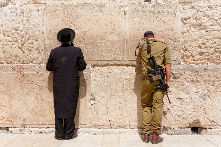 A soldier and Orthodox Jew pray at the Western Wall