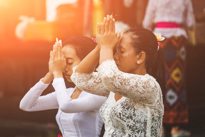 Two Indonesian women pray at a Hindu temple.