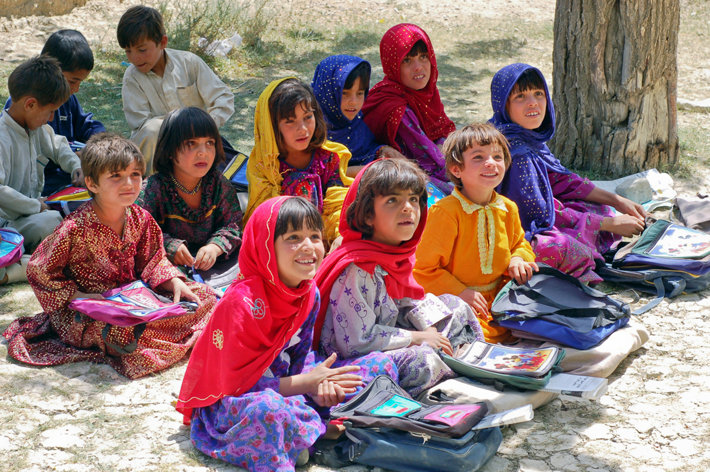 Schoolgirls sitting crosslegged on the ground wearing hijabs
