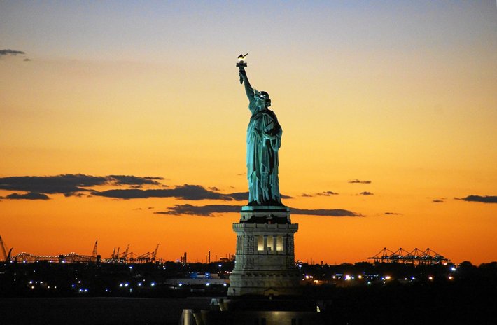 The Statue of Liberty with a sunset behind it