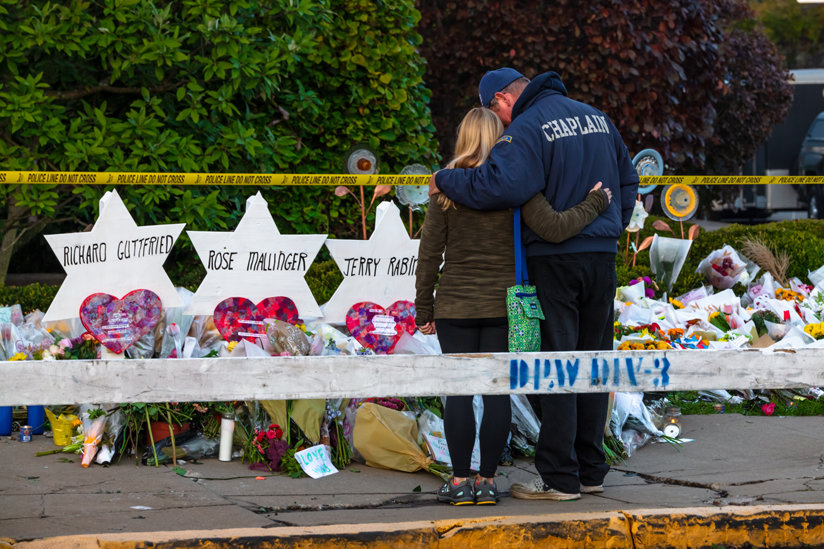 Man comforting woman in front of memorial