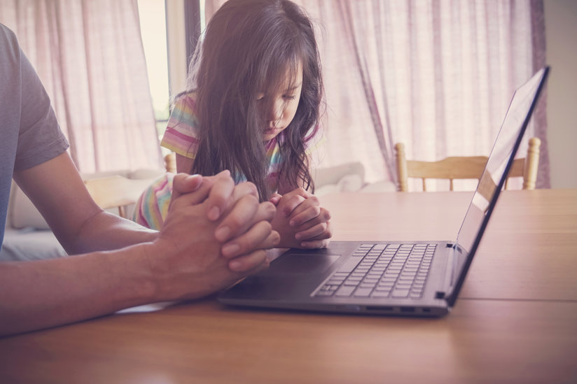 Little girl praying at lap top