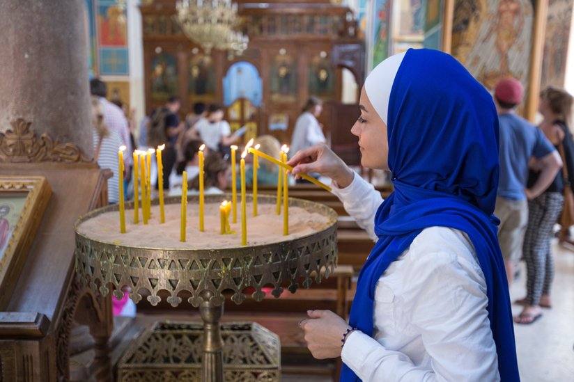 Woman in hijab lighting candles in a religious space