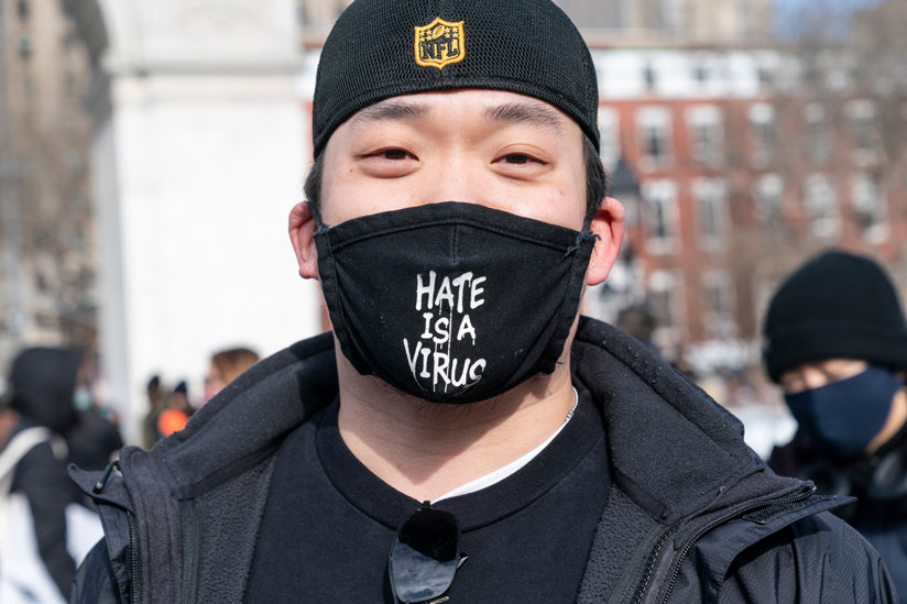 Man in a mask reading: hate is a virus