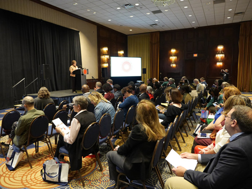 A woman speaking at a podium in front of an audience