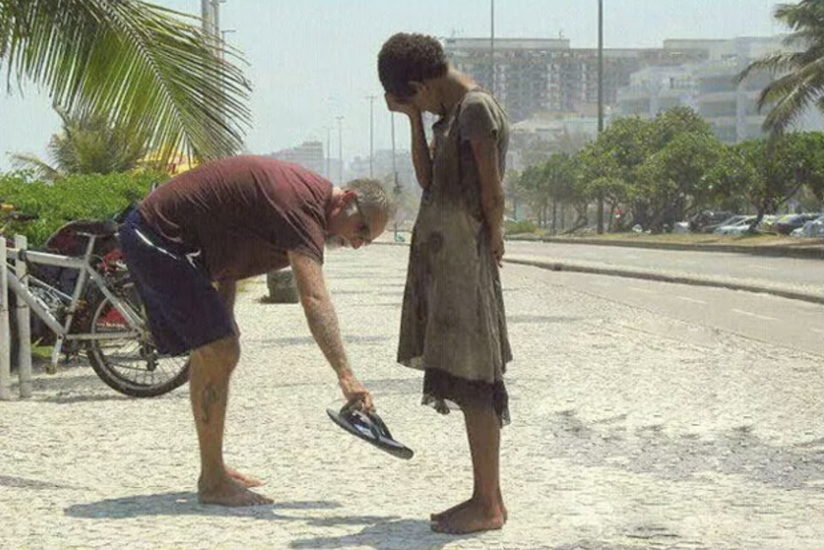 A man giving his shoes to a homeless girl in Brazil