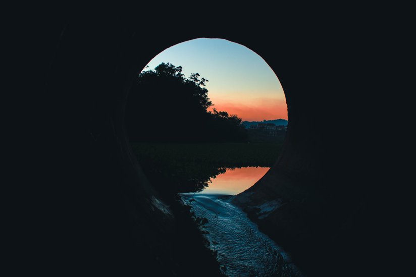 Tunnel with a lake and sky at the other end